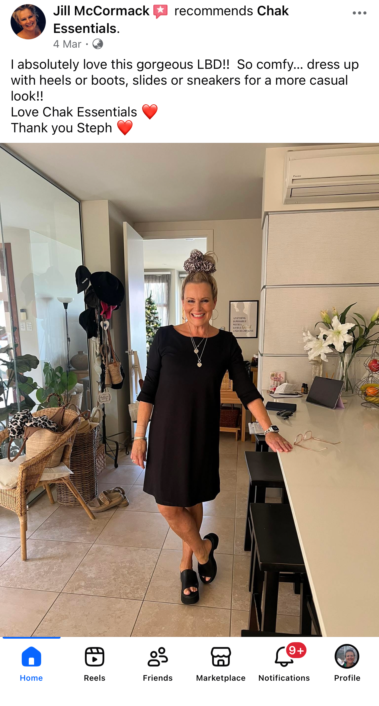 Woman in a black dress standing in a kitchen with a review of Chak Essentials on the screen.